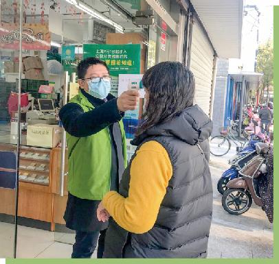 2020年2月20日，上海市崇明东滩鸟类自然保护区管理处党支部书记、主任沈帅作为东滩党员志愿者在给进出超市的市民测量体温.jpg